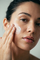 Young woman applying sunscreen to her face