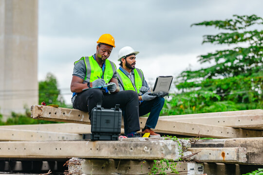 Railway engineer and technician inspecting concrete pier sections and construction debris