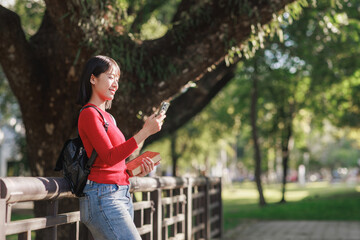Young asian woman student using smartphone outdoors