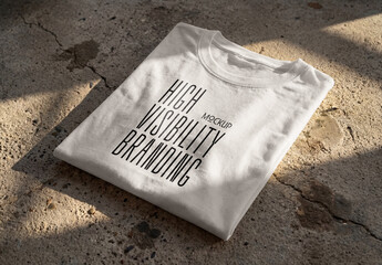 Template Mockup Folded T-Shirt on Concrete Surface with Natural Shadows