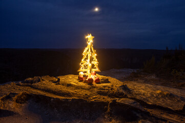 Little wooden Christmas tree illuminated at night with moon