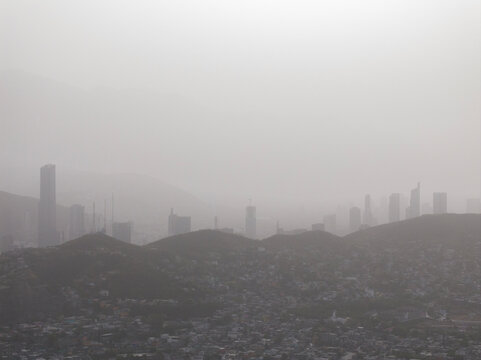 City skyline covered in thick smog and pollution near mountains