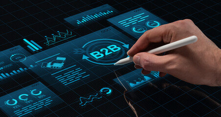Hand using digital pen to interact with futuristic B2B interface concept on high-tech screen with holographic HUD elements and glowing blue graphics.