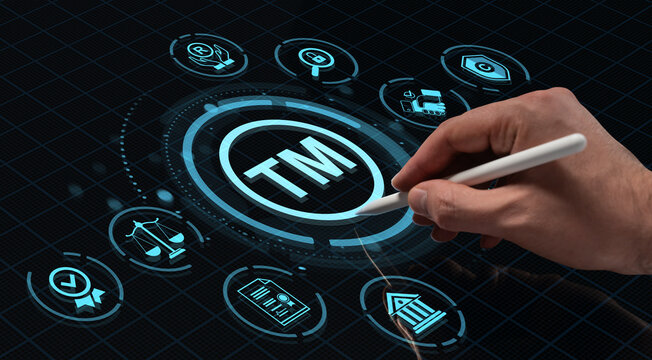 Hand holding digital pen touching holographic trademark icon on futuristic HUD interface with legal and copyright symbols on dark tech background. - Powered by Adobe