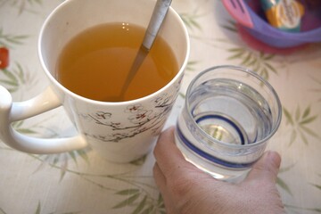 A large mug of tea placed beside a glass of water, offering a choice between two beverages.