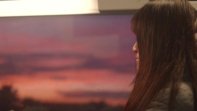Woman traveling on a train by the window, watching the sunrise over the city.