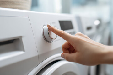 Woman hand selecting wash cycle on washing machine dial
