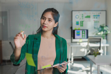 Young asian businesswoman brainstorming ideas on glass board