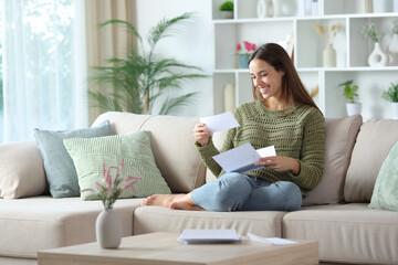 Fototapeta premium Happy woman in green reading check from letter at home