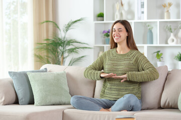 Obraz premium Happy woman in green doing yoga breathing exercises