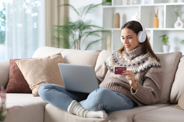 Obraz premium Serious woman in winter buying media online with card