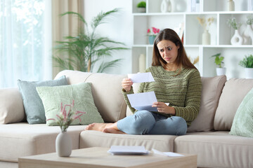 Obraz premium Suspicious woman in green checking bill on a couch at home