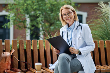 Portrait of a mature older female woman doctor or nurse and  health care worker using a smartphone...