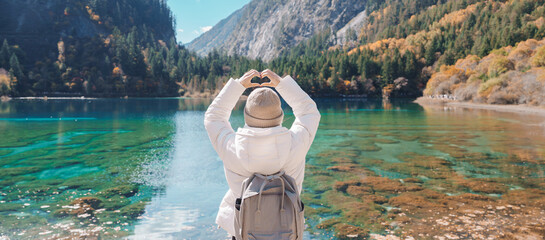 Happy woman traveler travel in jiuzhaigou national park in Sichuan, China. Tourist sightseeing Five...