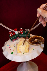 Hand Presenting Snow Roll Cake in Christmas Setting