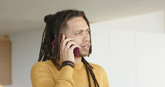 Mid-adult man answering magenta phone call in kitchen, expressing frustration then scrolling screen