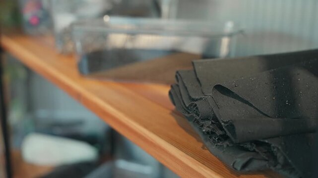 Stack of black textured material resting on wooden shelf