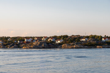 Fototapeta premium Vrango, Sweden - 09-08-2025 A beautiful summer sunset over the island Vrango in the Gothenburg archipelago with a view on fishing cabins hiding behind a pier of big rocks to protect them from the tide