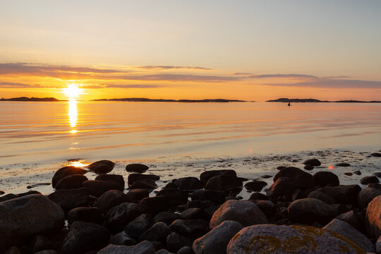 Beautiful summer evening with a spectacular sunset over the Gothenburg Archipelago and the calm water of the North Sea seen from the rocky coastline of the small island Vrango with a swimming jetty