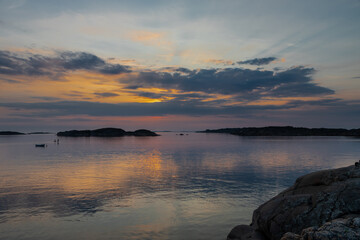 Fototapeta premium Colourful sunset over the Baltic Sea with and Swedish archipelago near Gothenburg, which is characterised by beautiful scenery and untouched nature with views on a wooden boardwalk to a small cottage,