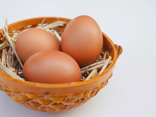 Several fresh chicken eggs are placed in bamboo basket on white background. It looks beautiful and delicious.
