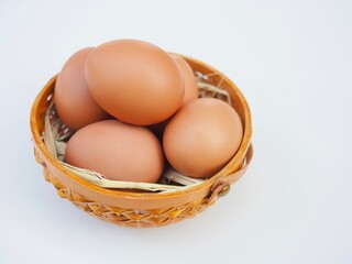 Several fresh chicken eggs are placed in bamboo basket on white background. It looks beautiful and delicious.