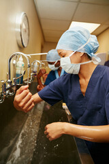 Surgeon, woman or washing hands in hospital with water for medical procedure, disinfection or...
