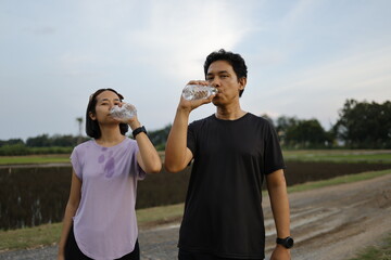 Woman and man drinking water after exercise