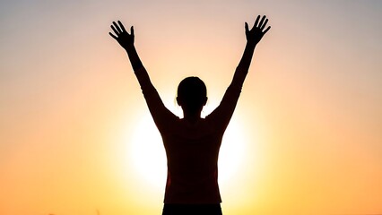Fototapeta premium Silhouette of a person with arms raised in triumph or joy against a vibrant orange and yellow sunset sky, symbolizing freedom and success.