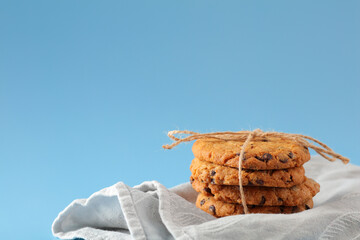 Rustic chocolate chip cookie stack tied with twine resting on soft gray fabric