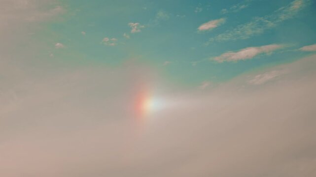 A subtle, soft sky with a faint vertical rainbow or sundog, blending warm and cool tones