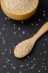 Quinoa seeds in wooden bowl and spoon with scattered grains