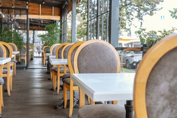 Elegant cafe terrace with wooden chairs and white tables for hospitality and dining concept