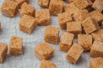 Brown sugar cubes scattered on a white cloth surface in a kitchen setting