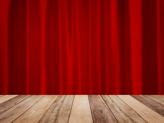 Wooden table top over abstract blurry red velvet curtain on stage.