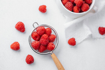 Raspberries in bowl and strainer on satin cloth for luxury food or dessert concept