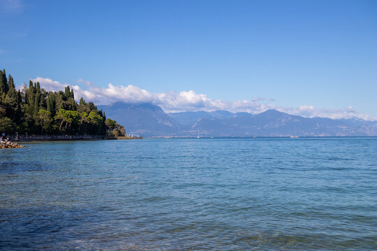 Lake Garda in sunny weather, crystal clear water and blue sky, popular Italian travel destination for summer vacation, tourism, and scenic European adventures - Powered by Adobe