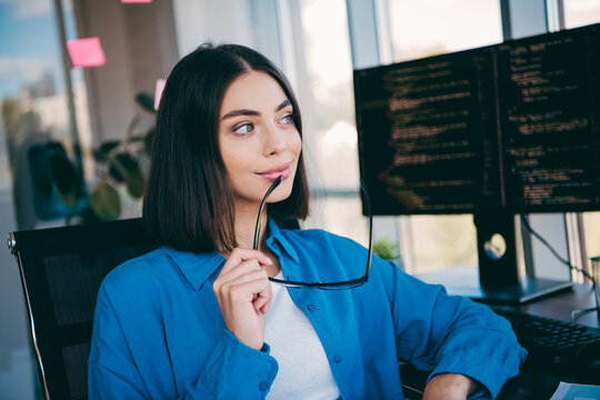 Businesswoman at a modern office reviewing code on a large monitor with glasses in hand - Powered by Adobe