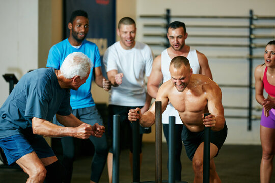 Fitness, weight sled and man in gym for challenge with personal training class for wellness. Health, workout and male person running for body strength with exercise in sports center for hobby.