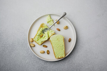 Pistachio ice cream cones on a plate with a spoon and nuts, top view.