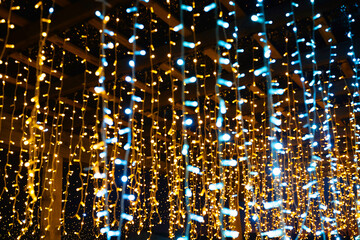 Warm yellow and cool blue holiday lights hanging in strands create a festive bokeh background