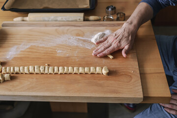 Ein Mann formt Vanillekipferl Kekse auf einem Holzbrett. Vorbereitung, Kekse backen, Weihnachten. 