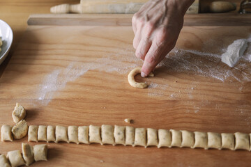 Ein Mann formt Vanillekipferl Kekse auf einem Holzbrett. Roher Teig, Vorbereitung, Weihnachten. 