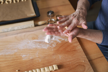 Ein Mann formt Vanillekipferl Kekse in seiner Hand. Roher Teig, Vorbereitung, Weihnachten.