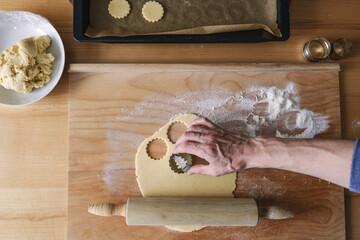 Ein Mann sticht Kekse auf einem ausgerollten rohen Teig aus. Weihnachten, backen, selbstgemacht, Draufsicht.