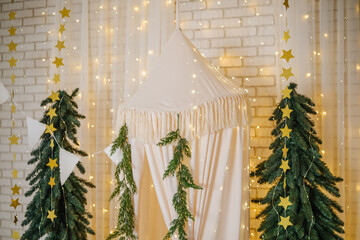 Christmas tree with festive gold stars and hanging canopy tent indoors with warm lights