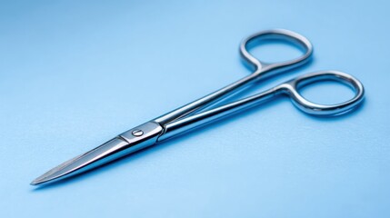 Scissors placed on a blue background with focus on sharp blades and handles during daytime