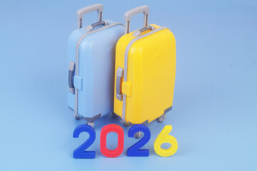 Two travel suitcases and numbers 2026 on blue background. Tourism and travel in year 2026.