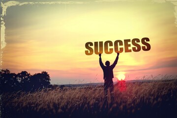 Person holding up the word success in a field at sunset