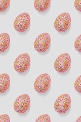 Colorful easter eggs in shiny sequins as minimal trend repeat pattern on light gray. Pop art still life close up photo of sparkling rhinestones pink egg, spring easter holiday concept, modern design.